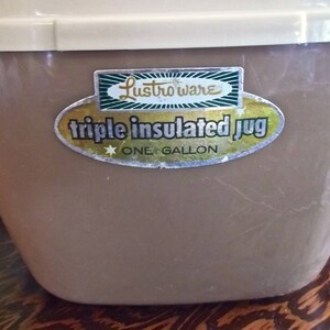 May include: A brown, one-gallon, triple insulated jug with a white lid. The jug has a sticker that says "Lustro-ware triple insulated jug one gallon".