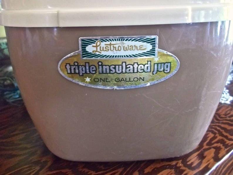 May include: A brown, one-gallon, triple insulated jug with a white lid. The jug has a sticker that says "Lustro-ware triple insulated jug one gallon".