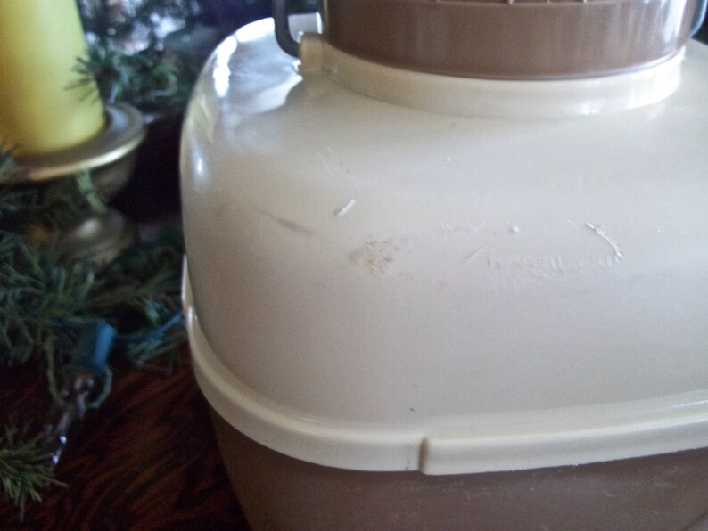 May include: A white and brown insulated beverage container with a lid and a handle. The container has a small scratch on the side.