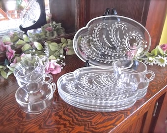 May include: Set of clear glass serving dishes with a wheat design. The set includes a large oval dish, four smaller round dishes, and four cups.