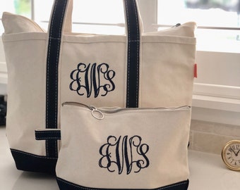 May include: Two canvas tote bags with black trim and a monogrammed design. The larger bag has a zippered top and the smaller bag has a zippered closure. Both bags feature the monogram "EWS" in a cursive font.