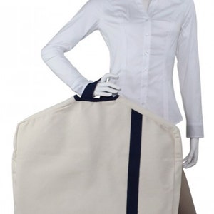 May include: A white garment bag with a navy blue handle and a navy blue stripe down the center. The bag is made of a durable fabric and has a zipper closure.