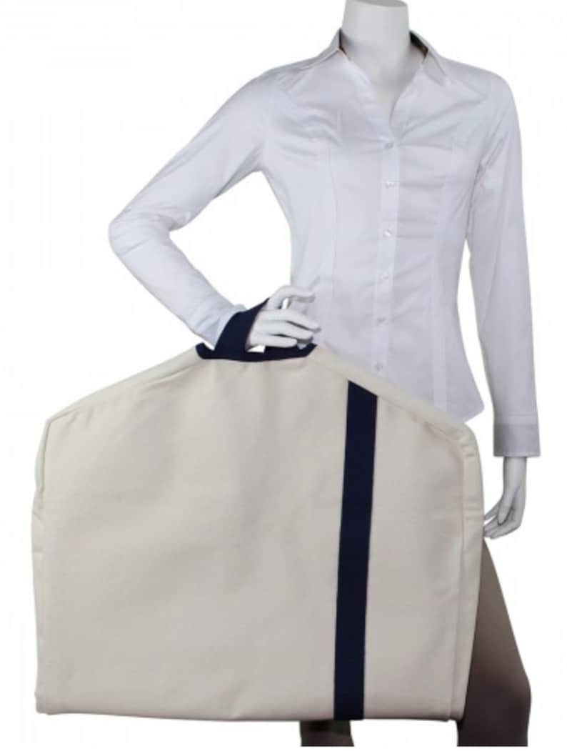May include: A white garment bag with a navy blue handle and a navy blue stripe down the center. The bag is made of a durable fabric and has a zipper closure.