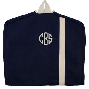 May include: A navy blue garment bag with a white stripe down the side and a white monogram "CBS" on the front.