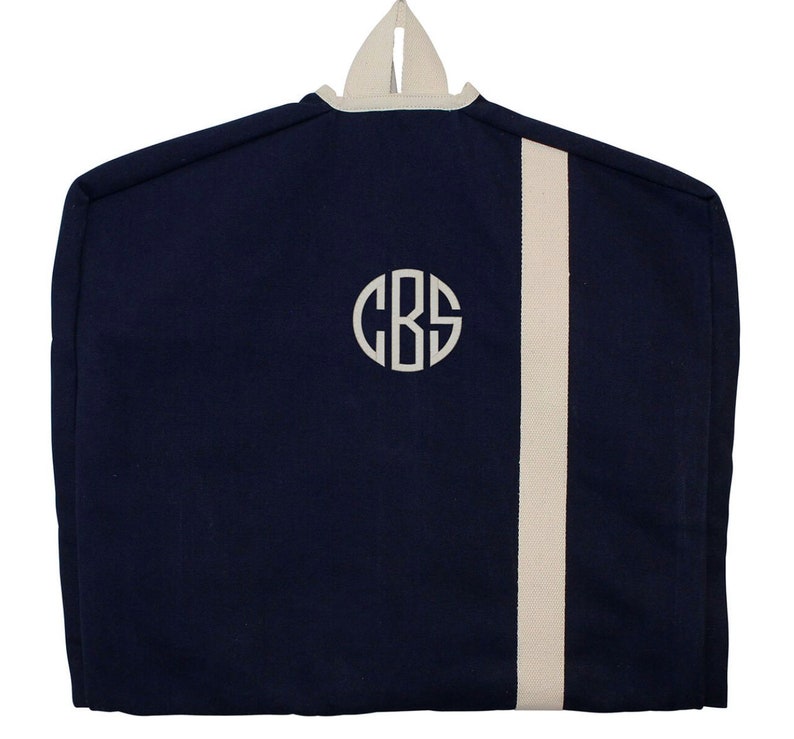 May include: A navy blue garment bag with a white stripe down the side and a white monogram "CBS" on the front.
