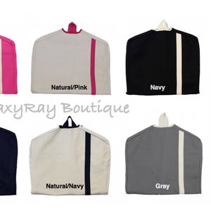 May include: Set of 6 garment bags in various colors, including pink, natural with pink trim, navy, black, natural with navy trim, and gray. Each bag features a hanger and a contrasting stripe down the side.