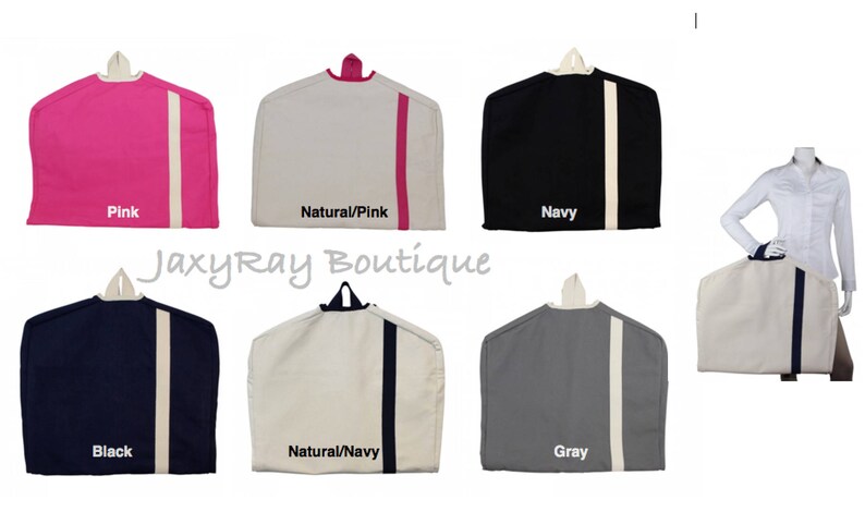May include: Set of 6 garment bags in various colors, including pink, natural with pink trim, navy, black, natural with navy trim, and gray. Each bag features a hanger and a contrasting stripe down the side.