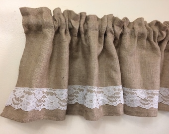 May include: A brown burlap valance with white lace trim. The valance is gathered and has a rustic look.