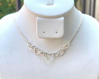 May include: A silver necklace with a chain and five interconnected heart-shaped links.