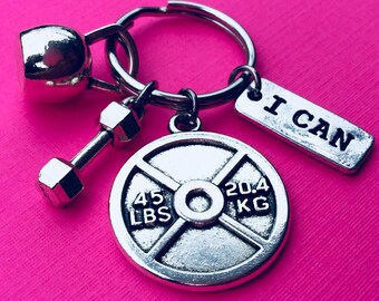 May include: Silver keychain with a dumbbell, a weight plate that says "45 LBS 20.4 KG", and a tag that says "I CAN".