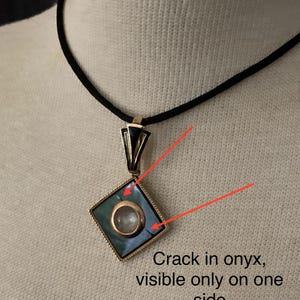 May include: A gold-toned pendant with a square, teal-colored onyx stone and a circular, clear stone in the center. The pendant hangs from a black cord. Text on the image reads: "Crack in onyx, visible only on one side."