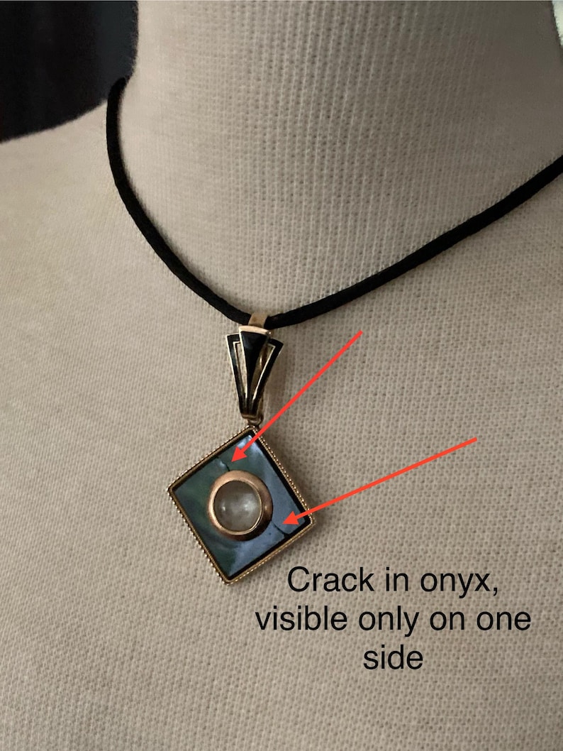 May include: A gold-toned pendant with a square, teal-colored onyx stone and a circular, clear stone in the center. The pendant hangs from a black cord. Text on the image reads: "Crack in onyx, visible only on one side."