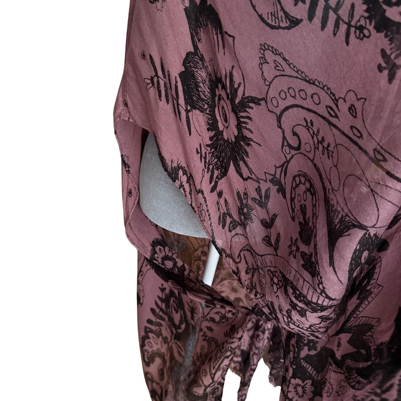 Puede incluir: Una tela de estampado floral rosa y negro con un patr&oacute;n paisley. La tela es suave y fluida, y los colores son apagados y elegantes.