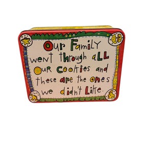 May include: A red, green, and yellow tin cookie container with the text "Our Family went through aLL Our Coolties and these are the ones we didn't Litte."