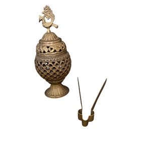 May include: A gold-colored, ornate incense burner with a peacock finial. The burner has a pierced design and sits on a pedestal base. A matching gold-colored tweezer is next to the burner.