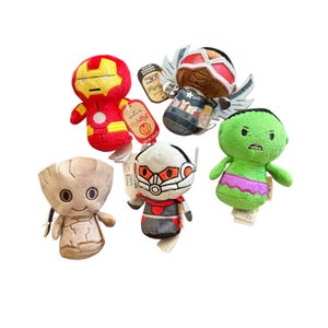 May include: A collection of plush Marvel superhero characters, including Iron Man, Thor, Captain America, Hulk, Ant-Man, and Groot. Each character is brightly colored and features a unique design. Each plush has a tag attached.