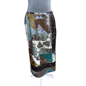 May include: A knee-length skirt with a patchwork design. The skirt features a mix of colors including brown, teal, blue, and white. The fabric has a textured appearance. The skirt is displayed on a mannequin.