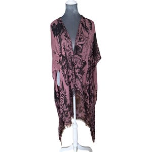 Puede incluir: Un kimono de color rosa y negro con estampado y flecos en el dobladillo.