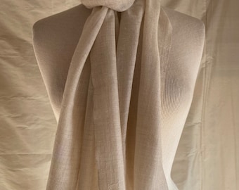 May include: A cream-coloured scarf made of a soft, lightweight fabric. The scarf is draped over a mannequin and has a fringed edge.
