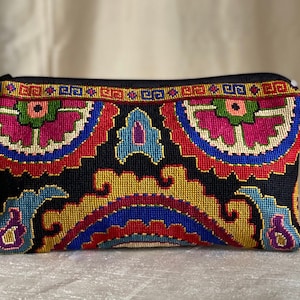 Puede incluir: Una bolsa de cremallera bordada de colores con fondo negro y intrincados patrones florales y geométricos en tonos rojos, azules, amarillos, verdes y rosas.