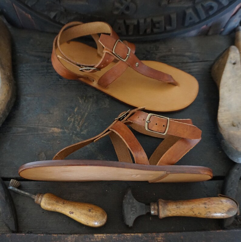 Pu&ograve; includere: Due paia di sandali in pelle marrone con chiusura a fibbia. I sandali hanno un design semplice e sono realizzati in pelle di alta qualit&agrave;.