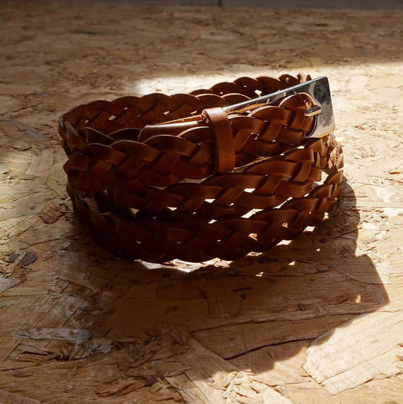 May include: A brown leather braided belt with a silver buckle.