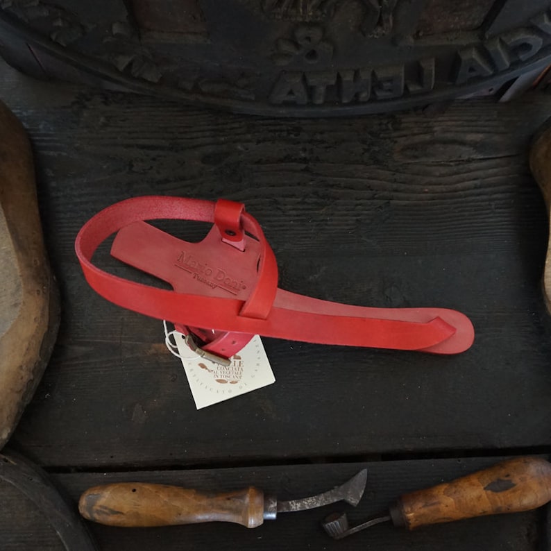 May include: Red leather sandal with a strap across the foot and a buckle fastening. The sandal is handmade and has a tag that says "Made to Order".