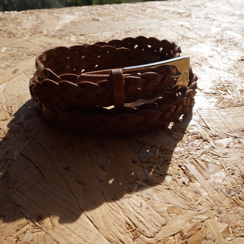 May include: A brown leather braided belt with a silver buckle.