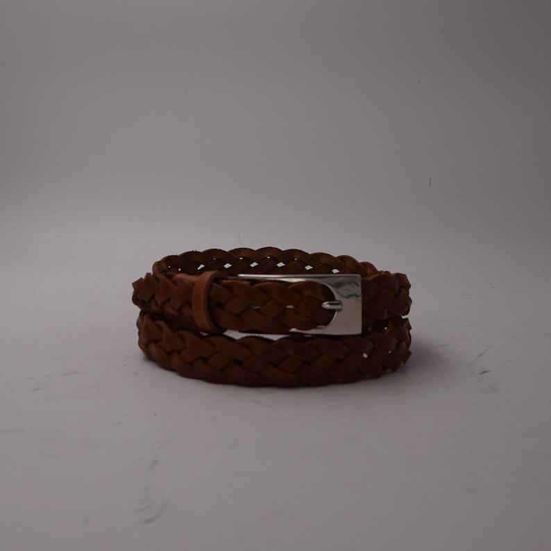 May include: A brown leather braided belt with a silver buckle.