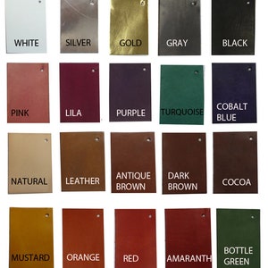 May include: A collection of rectangular leather swatches in various colors, including white, silver, gold, gray, and black. Additional colors include pink, lila, purple, turquoise, and cobalt blue. Other colors are natural, leather, antique brown, dark brown, cocoa, mustard, orange, red, amaranth, and bottle green.