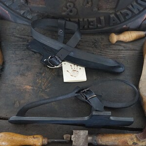 May include: Black leather sandals with a buckle fastening. The sandals are handmade and have a simple design.
