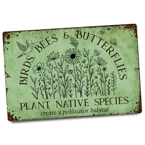 May include: A rectangular, distressed metal sign with a light green background and black text and illustrations. The sign reads "BIRDS BEES & BUTTERFLIES" and "PLANT NATIVE SPECIES" with illustrations of flowers, a hummingbird, bees, and butterflies.