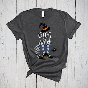 Könnte beinhalten: Ein dunkelgraues T-Shirt mit einer weißen Grafik einer Hexe mit dem Text "GIGI witch" darauf.