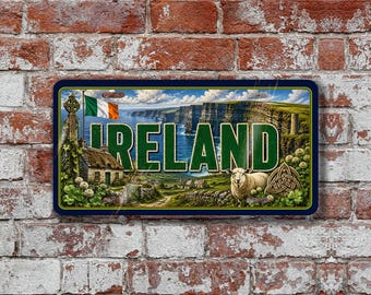 May include: A rectangular metal sign featuring the word IRELAND in large green letters. The background displays the Cliffs of Moher, a stone cottage, a sheep, a Celtic cross, a triquetra symbol, and the Irish flag under a blue sky.