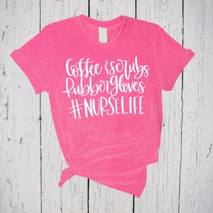 May include: Pink t-shirt with white text that reads "Coffee & Scrubs Rubber Gloves #NURSELIFE"