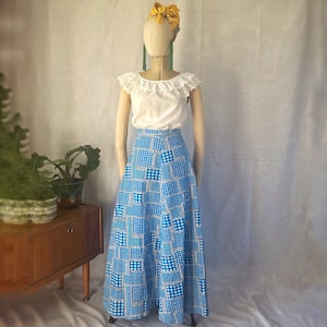 May include: A white peasant top with a lace trim and a blue and white gingham patchwork maxi skirt.