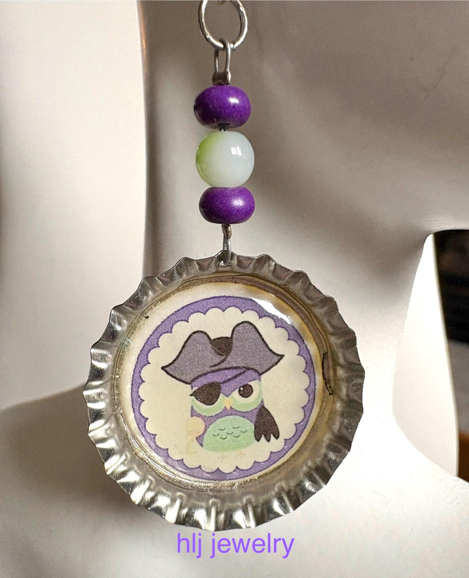 Pirate Owl Dangle Earrings With Silver Bottlecap with A Pirate Owl and Green and Purple Beads