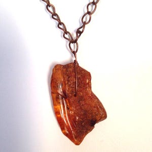 May include: A copper chain necklace with a large, irregular piece of amber as a pendant.