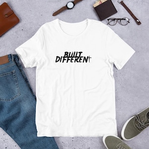 May include: White t-shirt with black text that reads "BUILT DIFFERENT".