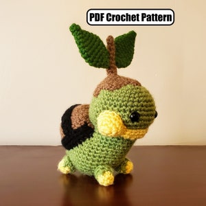 May include: A crocheted green and brown plush toy with yellow accents and black eyes. The toy has two green leaves on top of its head.  PDF Crochet Pattern.