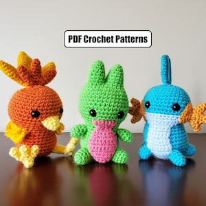 Pode incluir: Três brinquedos de pelúcia de crochê: um pássaro amarelo e laranja, um sapo verde e um peixe azul e laranja.  Padrões de crochê PDF.