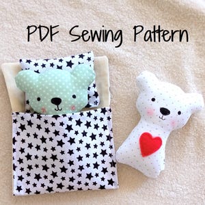 May include: A handmade bear toy with a red heart, next to a miniature bed set. The bed set includes a pillow and blanket with a star pattern. The bear in the bed is mint green with white polka dots. The text "PDF Sewing Pattern" is visible.