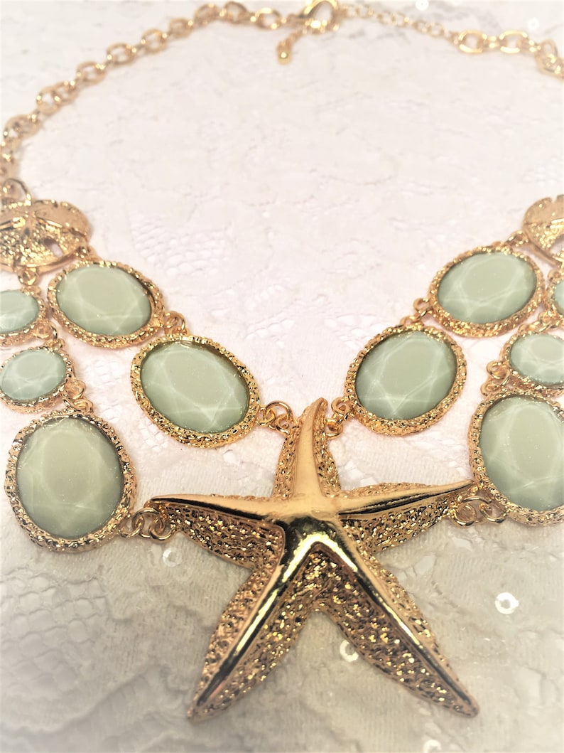 Good Condition. Chunky Chain Gold Tone Starfish Necklace with Lucite Light Green Sparkly Stones and Gold Tone Sand Dollar Medallions
