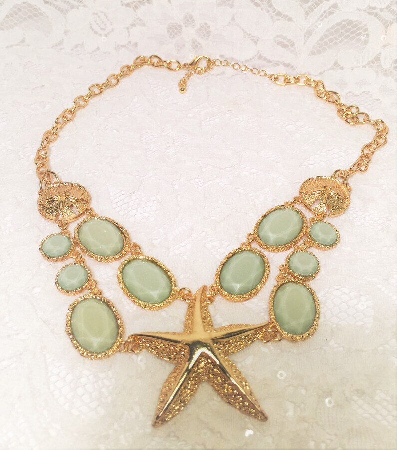 Good Condition. Chunky Chain Gold Tone Starfish Necklace with Lucite Light Green Sparkly Stones and Gold Tone Sand Dollar Medallions