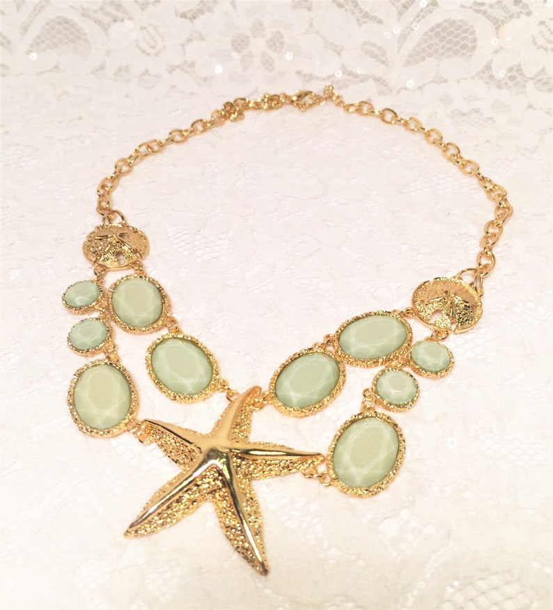 Good Condition. Chunky Chain Gold Tone Starfish Necklace with Lucite Light Green Sparkly Stones and Gold Tone Sand Dollar Medallions