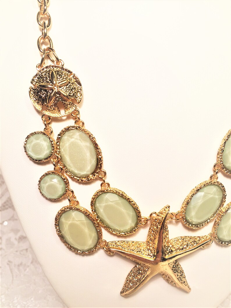 Good Condition. Chunky Chain Gold Tone Starfish Necklace with Lucite Light Green Sparkly Stones and Gold Tone Sand Dollar Medallions
