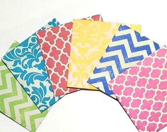 May include: Six small decorative paper envelopes with different patterns. The envelopes are in shades of green, blue, pink, yellow, and red. The patterns include a chevron, a floral design, and a geometric pattern.