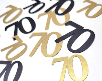May include: Black and gold confetti with the number 70 printed on each piece. The confetti is scattered on a white surface.