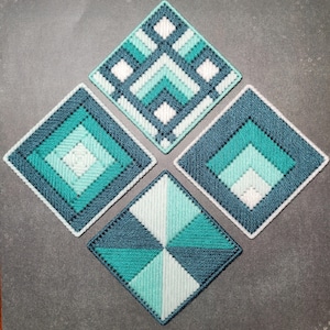 May include: Four square coasters featuring geometric needlepoint patterns in shades of teal, turquoise, and white. Each coaster displays a unique arrangement of stitched lines and shapes, creating a cohesive set of textile home accessories.