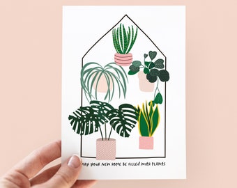 May include: A white card with a black outline of a house filled with potted plants. The text "May your new home be filled with plants" is at the bottom of the card.